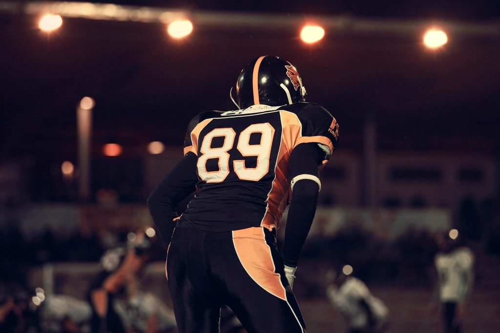 A receiver reaches for the ball under stadium lights